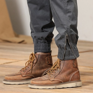 Close-up of caramel brown leather moc toe boots with white stitching and thick rubber sole