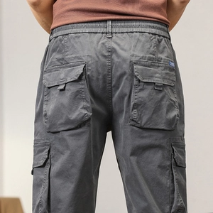 Detail view of elastic drawstring waistband and large side cargo pockets on dark gray pants
