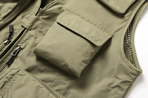 Détail du gilet extérieur vert olive montrant plusieurs poches et un tissu en maille aéré
