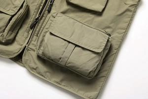 Détail du gilet utilitaire vert armée montrant plusieurs poches et un tissu durable