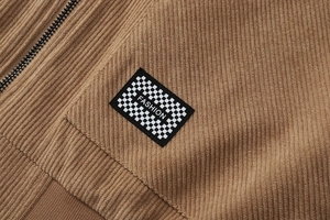 Detail van bruine corduroy stof met dambordpatroon patch en metalen rits van hoge kwaliteit