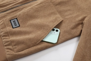 Detail van bruin corduroy jack met grote zak, modelabel en de textuur van de metalen rits