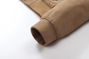Detailopname van de bruine corduroy jas mouw met elastische geribbelde manchetten