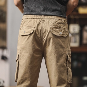 Détail du pantalon cargo kaki avec taille élastique et poches à rabat et bouton métal