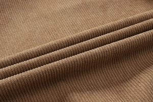 Macro-opname van bruine corduroy stof met verticale ribbels en zachte warme textuur