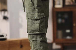 Détail d'un pantalon cargo vert armée avec poche latérale à rabat et attache en métal argenté