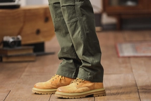 Détail du pantalon cargo vert armée avec des bottes classiques en nubuck jaune au sol