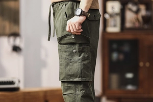 Vue détaillée du pantalon cargo olive avec grandes poches latérales et boutons-pression