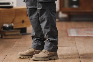 Détail du pantalon cargo stretch gris foncé et bottines de travail en daim marron