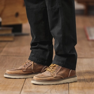 Gros plan du pantalon cargo noir pour hommes avec des bottes vintage en cuir marron