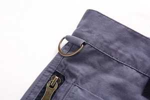 Detailed macro view of the gray cotton cargo pants waist with metal D-ring and zipper