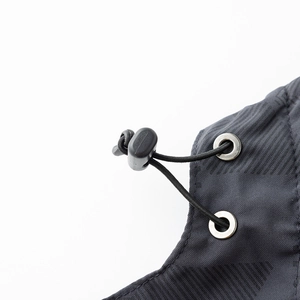 Detalle macro de cordón ajustable con hebilla y ojales metálicos en chaqueta gris