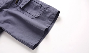 Detail of grey-blue cargo shorts showing durable cotton twill fabric and metal zipper pocket