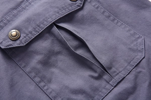 Macro detail of cotton cargo shorts showing a side pocket with a vintage metal button