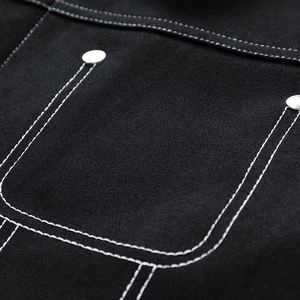 Detail of black suede jacket featuring contrast white stitching and metal rivets on pocket