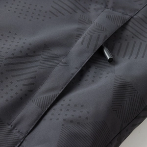 Detalle macro de tela cortavientos gris oscuro con estampado geométrico y bolsillo con cremallera