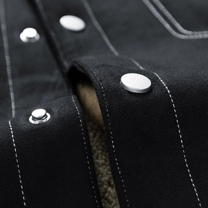 Detail of black suede jacket with warm lamb fleece lining and silver metal buttons