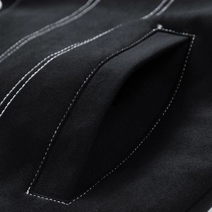 Detail view of black faux suede jacket featuring contrasting white double stitching on the pocket