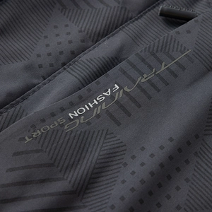 Detalle macro de tela gris oscuro con estampado geométrico y texto deportivo moda