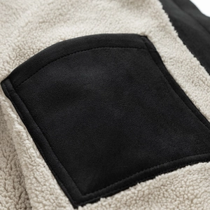 Close-up detail of warm sherpa fleece texture with a contrasting black suede pocket on the jacket
