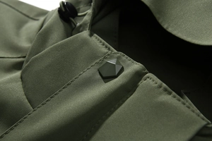 Detail van legergroene outdoor jas met matte vijfhoekige knoop en ripstop weefsel