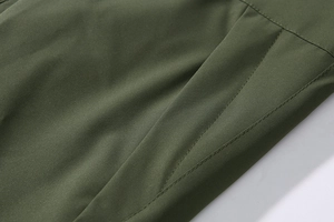 Detail van dubbele stiksels en zakken op de olijfgroene outdoor jas voor heren