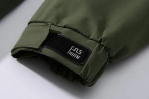 Detailopname van de manchet van een groene outdoorjas met verstelbare klittenbandsluiting