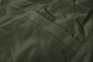 Detailopname van de legergroene outdoorjas stof met versterkte stiksels en twill textuur