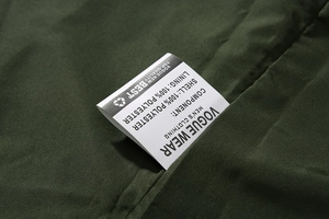 Detailweergave van het 100% polyester label op een groene outdoor herenjas