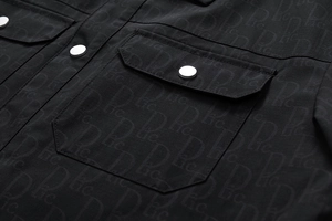 Détail de la veste noire avec motif D lic et bouton-pression en métal argenté