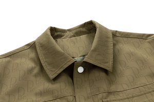 Détail de la veste vert olive avec motifs de lettres et bouton-pression argenté