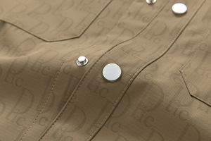 Gros plan détaillé du tissu kaki de la veste avec motif monogramme et bouton en métal