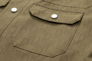 Détail de la veste olive en tissu ripstop avec imprimé lettres et bouton pression