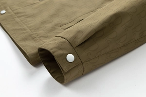 Détail d'une manche de veste vert armée avec tissu quadrillé et bouton-pression en métal