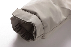 Dettaglio dei polsini regolabili antivento con cinturini in velcro su giacca beige