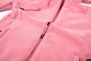 Dettaglio della felpa con cappuccio in pile rosa con texture morbida e chiusura a zip