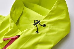 Detailed macro view of fluorescent yellow outdoor jacket with red zipper and adjustable cord