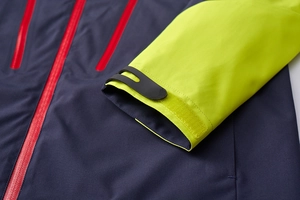 Detail of waterproof red zipper and velcro cuffs on a navy blue outdoor shell jacket