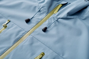 Macro detail of sky blue jacket with contrast lime green zipper and hood drawstring