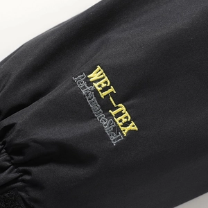 Dettaglio macro del ricamo WEI-TEX Performance Shell sul polsino della giacca a vento