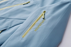 Detail of light blue waterproof jacket featuring a glued zipper and EXPLORATION embroidery