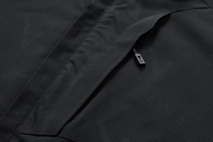 Detail der wasserdichten Outdoorjacke mit matten geometrischen Mustern und Reißverschlusstasche