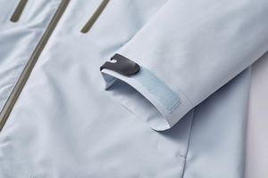 Macro detail of the light blue hiking jacket featuring waterproof zippers and velcro cuffs