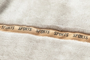 Detail der weichen grauen Fleece-Textur mit besticktem khakifarbenem Sportband auf Outdoor-Jacke