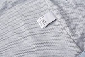 Macro view of outdoor jacket interior showing 100% polyester mesh and washing label
