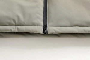 Dettaglio delle cuciture del tessuto kaki e della cerniera nera sulla giacca outdoor tecnica