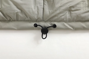 Dettaglio del cordoncino elastico regolabile e del fermo sull'orlo di una giacca outdoor