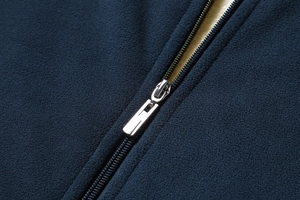 Close-up of high-quality silver zipper on navy blue fleece jacket with warm white lining