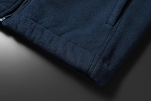 Detail view of navy blue fleece jacket hem with smooth zipper and side pocket stitching