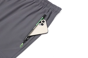 Dettaglio dei pantaloni sportivi ad asciugatura rapida con tasca zip e nastro logo